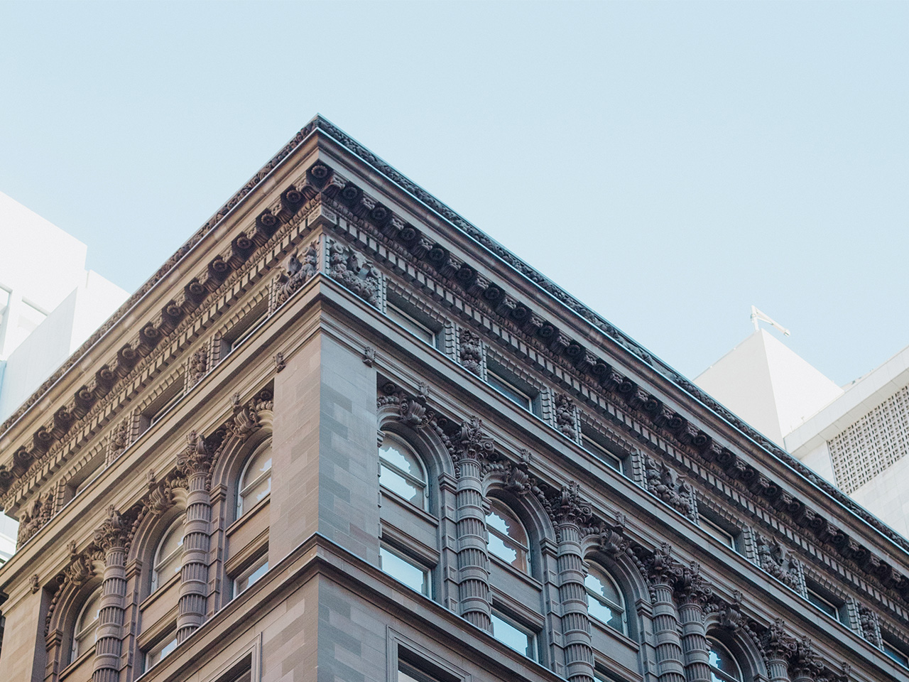 Corner view of a classic architectural building with detailed cornice against a clear blue sky.